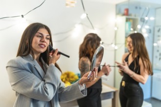 Friends women applying makeup and styling hair, preparing for a festive new year's eve party or