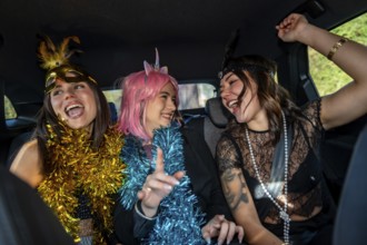 Young happy women dressed in costumes and festive garlands celebrating, laughing, and having fun