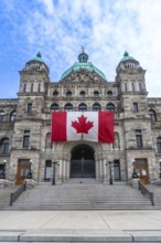 Large canadian flag hanging from the british columbia parliament buildings in victoria, british