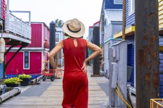 Tourist wearing a red jumpsuit and straw hat walking at fisherman's wharf park, a colorful floating