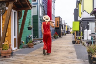 Tourist wearing a straw hat and a red jumpsuit is walking on a wooden walkway exploring the
