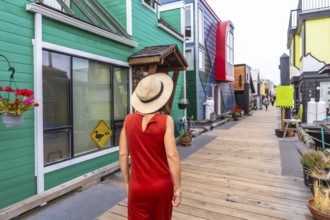 Tourist wearing a straw hat and orange dress walking along a wooden walkway, visiting vibrant