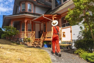 Tourist wearing a straw hat and orange jumpsuit walking along a gravel path beside a vibrant wooden