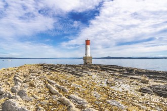 Red and white lighthouse rising from a rocky, textured coastline in chemainus, vancouver island,