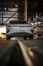 White car in front of warehouse structure at sunset on rails, VW ID4 electric car, Deer Carsharing,