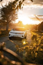 White car on a country road at sunset with silhouettes, VW ID4 electric car, Deer Carsharing, Calw,