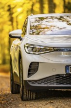 Close-up of a white car on a forest road in autumn, VW ID4 electric car, Deer Carsharing, Calw,
