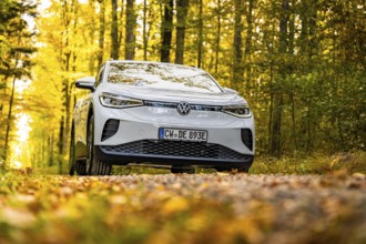 Front view of a white car on a forest road in autumn, VW ID4 electric car, Deer Carsharing, Calw,