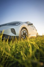 White car close-up on green field under clear sky, VW ID4 electric car, Deer car sharing, Calw,