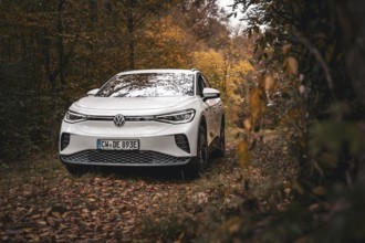 A white Volkswagen in autumn forest with lots of leaves, VW ID4 electric car, Deer Carsharing,