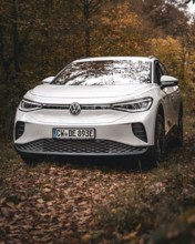A white Volkswagen surrounded by autumn leaves in the forest, VW ID4 electric car, Deer Carsharing,