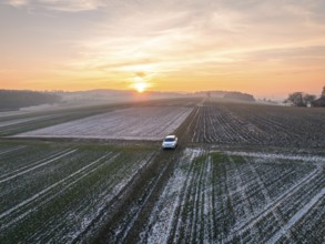 A white car is parked in a vast, frozen field at sunrise, VW ID4 electric car, Deer Carsharing,
