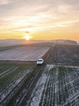 A white car is parked in a frozen field at sunrise, VW ID4 electric car, Deer Carsharing, Calw,