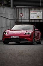 Red Porsche Taycan stands in front of a modern building on paved area, Porsche Taycan, Deer