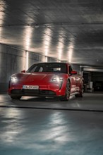 Red Porsche Taycan parked in an illuminated underground car park with an urban atmosphere, Porsche