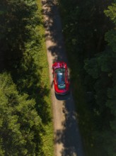 Bird's eye view of red sports car on a forest road, Porsche Taycan, Deer Carsharing, Calw, Germany