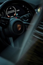 Close-up of a modern steering wheel with speedometer and LED indicators in a car, Porsche Taycan,