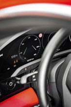 Detail of a dashboard with speedometer and steering wheel, accent color red, Porsche Taycan, Deer
