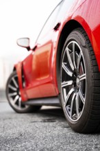 Side view of a red vehicle focusing on the front wheel, Porsche Taycan, Deer Carsharing, Calw,