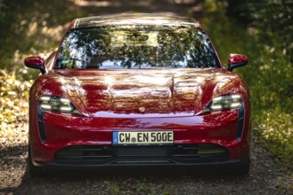 Close-up of a red car on a forest path, sunbeams in nature, Porsche Taycan, deer car sharing, Calw,