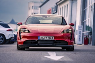 Red car of elegant design parked in an urban square, Porsche Taycan, Deer Carsharing. Calw, Germany