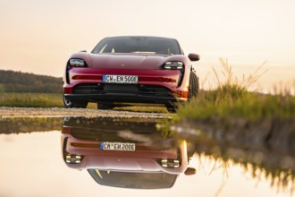 Red car reflected in a body of water at sunrise, Porsche Taycan, deer car sharing. Calw, Germany