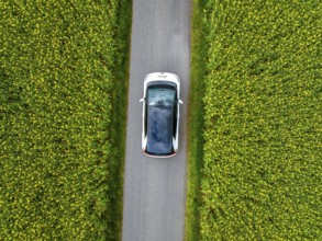 Aerial view of a car on a narrow road surrounded by green fields, ID3 VW, deer car sharing. Calw,