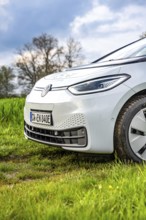 Side view of a wet car on a green field under cloudy sky, ID3 VW, deer car sharing. Calw, Germany