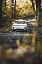 A car is parked on a forest path surrounded by autumn atmosphere and sun rays, VW ID4 electric car,
