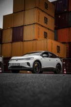 Car in front of tall, dark containers in industrial area, VW ID4 electric car, Deer Carsharing,