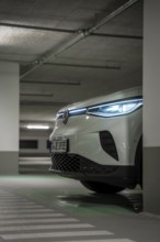 A car in an underground garage with headlights on at night, VW ID4 electric car, Deer Carsharing,