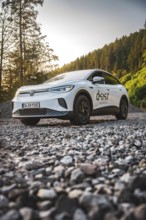 A car on a gravel path on the edge of a forest at sunset, VW ID4 electric car, Deer Carsharing,