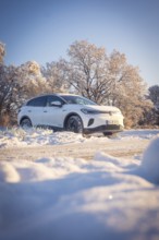 White car in snowy landscape with sunny sky and trees, VW ID4 electric car, Deer Carsharing, Calw,
