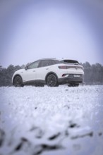 A car on snowy ground against a wooded background, VW ID4 electric car, Deer Carsharing, Calw,