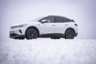 A car is standing in the snow surrounded by a wintry landscape, VW ID4 electric car, Deer