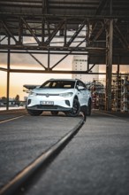 White car in industrial setting at sunset, VW ID4 electric car, Deer Carsharing, Calw, Germany