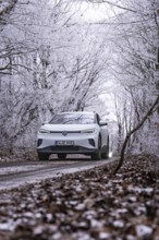 White car on snowy road in a snowy forest, VW ID4 electric car, deer car sharing, Calw, Germany