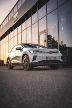 White car in front of a modern building at sunset, VW ID4 electric car, Deer Carsharing, Calw,