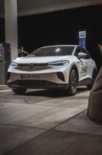 White car at a gas station at night, illuminated, VW ID4 electric car, Deer Carsharing, Calw,