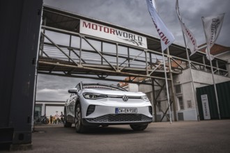White car in front of Motorworld building with construction site atmosphere, VW ID4 electric car,