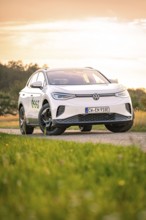 A car on a dirt road at sunset with a colorful sky, VW ID4 electric car, Deer Carsharing, Calw,