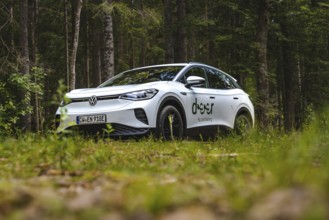 White Volkswagen in the forest, photographed from near the ground, VW ID4 electric car, Deer