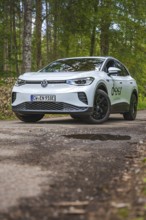 White car driving on a forest path surrounded by trees, VW ID4 electric car, Deer Carsharing, Calw,