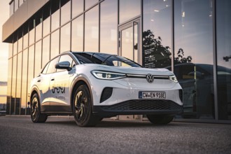 A white car in front of a modern building at sunset, VW ID4 electric car, Deer Carsharing, Calw,