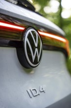 VW logo with rear light of a car in daylight in the forest, VW ID4 electric car, Deer Carsharing,