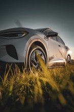 Low perspective shot of a car in a meadow at sunset, VW ID4 electric car, Deer Carsharing, Calw,