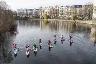 Water sports enthusiasts dressed up as Santa Claus ride SUPs on the Spree on the banks of the