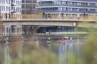 Water sports enthusiasts dressed up as Santa Claus ride SUPs under the Hansa Bridge on the Spree in