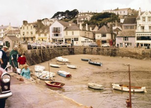 Historic waterfront buildings, boats at low tide in harbour at St Mawes, Cornwall, England, UK, c