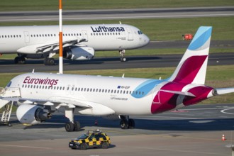 Lufthansa Airbus A321-200 on taxiway for takeoff, Eurowings Airbus parks outside position,